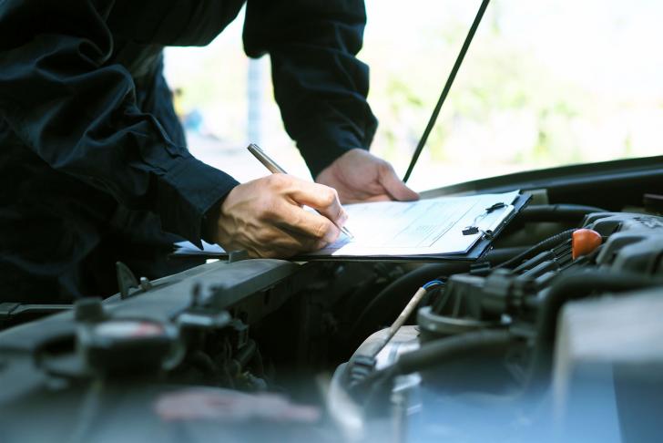 Automechaniker füllt Prüfbericht aus