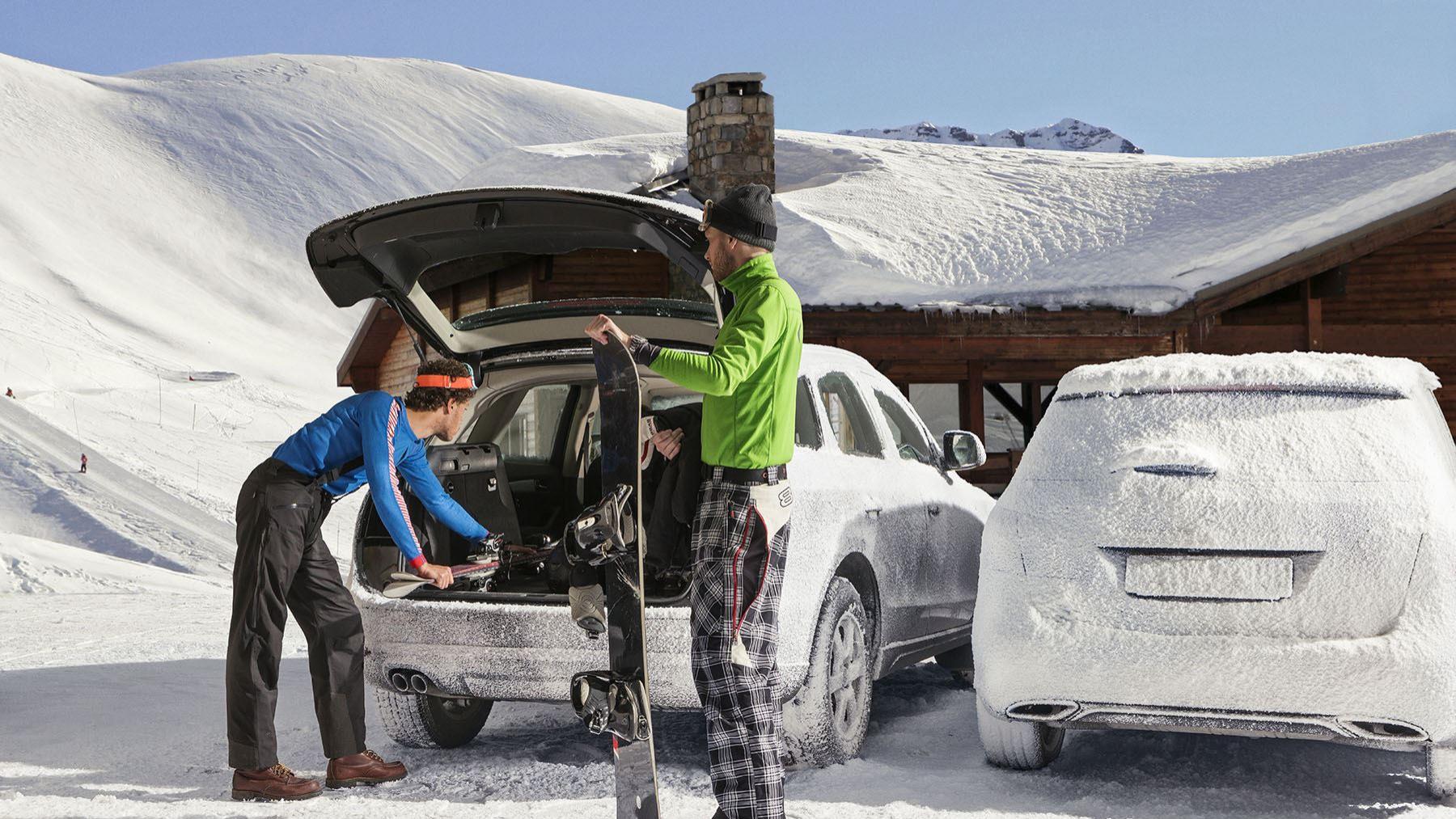 Snowboarder stehen an geönnetem Kofferaum und beladen